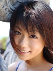 Lovely Japanese model smiles as she poses in her bikini on the beach